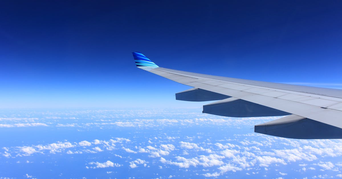 Scenic view of an airplane wing flying high above the clouds on a clear day.
